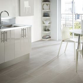 Modern kitchen with white high gloss units with a light slate tile effect flooring