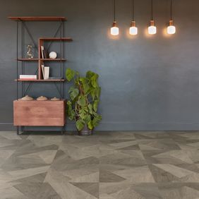Oak effect flooring in a prisma style laid in a room with dark grey wall and a shelving unit