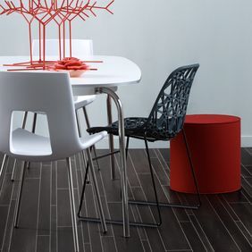 Black slate effect flooring in a dining room with white table and red accessories 