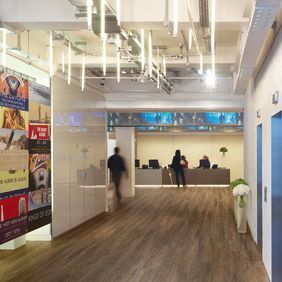 Modern office reception with wall art alongside white high gloss panelled walls and Huckleberry Oak flooring 