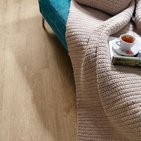 Close up of edge of sofa featuring light wood effect flooring in Cashmere Oak 