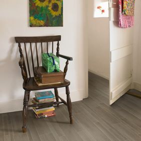 Slate effect flooring in a childerns bedroom with a wooden reading chair and bright flag bunting hung around the walls. 