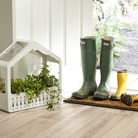 Light oak effect wood flooring in a back door area with a dirt mat and wellington boots 