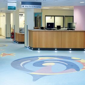 Blue homogeneous flooring in a hosptial reception area with murals in the flooring 