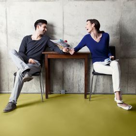 Seating area with green flooring with a man and woman sat down laughing