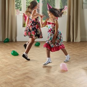 Light wood effect flooring in a parquet design with two girls dancing 
