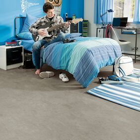 Concreet effect flooring in a bedroom with a boy playing guitar on the bed