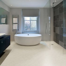  Neutral colour safety flooring in a modern bathroom with large round bath and walk in shower