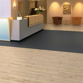 Reception desk with light wood effect flooring laid alongside Pearlazzo Charcoal 