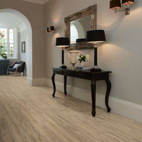 Hallway with dark wood console and lamps featuring light wood effect flooring in Quayside Oak 