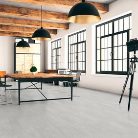 Light grey coloured flooring in a large room with open beams on the ceiling and a large table with chairs