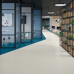 Light coloured flooring laid in an office setting with dark blue sections for privacy 