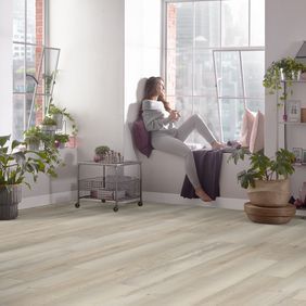 Woman sat on the window seatingwith pink accessories featuring light oak wood effect flooring
