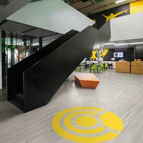 Black Office stairs reception area with seating and white oak effect flooring featuring a Expona Flow colour Flaxen design 