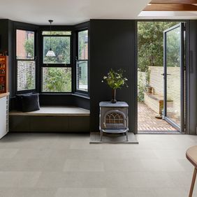 Grey stone effect flooring laid in a kitchen with a log burner, open door and a bay window