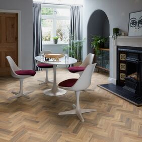 Oak effect flooring laid in a small parquet style in a dining room with a white table and chairs