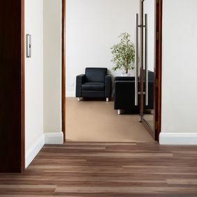 Office corridor with black leather chairs for seating area with walnut effect flooring laid alongside Pearlazzo PUR