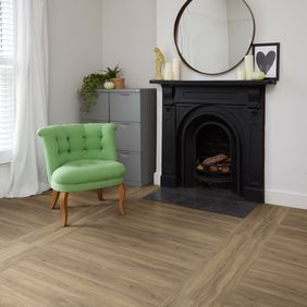 Black matt fire place with green cushioned chair with light wood oak effect flooring laid in a Double plank tramline 