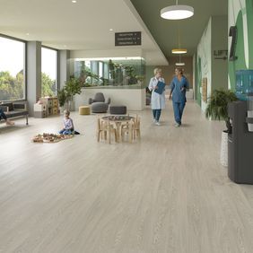 Oak effect flooring laid in a hospital waiting area with people