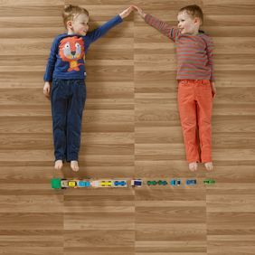 Two boys playing lay down playing with trains featuring ash wood effect flooring 