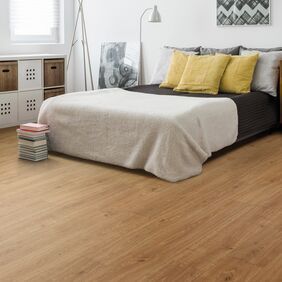 Oak effect flooring straight laid in a bedroom with white bedding and yellow cushions