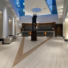 Modern reception area with seating with light oak flooring and V design created out of a dark oak flooring 