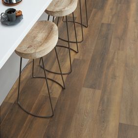 Close up of dark oak wood effect flooring with stools around a breakfast bar