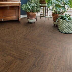 TLC Original in Walnut laid next to a piano and various potted plants