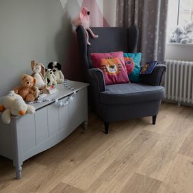 Oak effect flooring in a nursery room with a cuddle chair and teddies