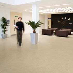 Cream colour stone effect flooring in a commercial corridor with a seating area 