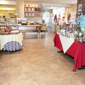 Warm coloured stone flooring in a bakery shop with cakes and jams on display