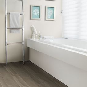 Slate effect flooring in a bathroom with a white bath and towel ladder