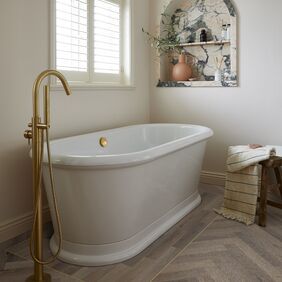 Oak effect flooring laid in a large parquet style in a bathroom with a freestanding bath