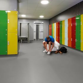 Grey colour safety flooring in a changing room with multi coloured lockers 
