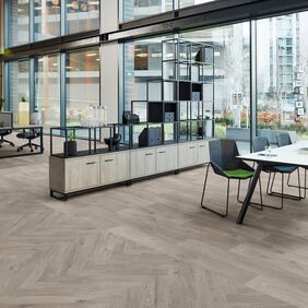 Oak effect flooring laid in an open office space with large glass panel windows