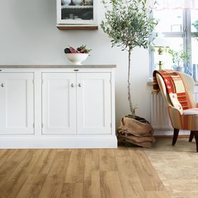 Light oak wood effect flooring in a family living room area with a reading chair and window 