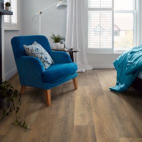 Dark oak wood effect flooring with a Blue velvet armchair and floor lamp 
