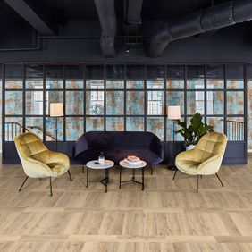 Oak effect flooring laid in a trendy waiting area with blue and yellow velvet chairs
