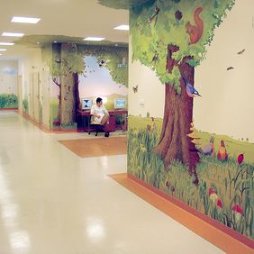 Children's hospital ward with light coloured flooring and woodland mural on the wall