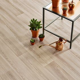 Close up of light oak wood effect flooring with a side table and plants for decoration 