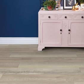 Light wood effect flooring with a baby pink dresser 