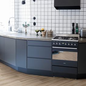 Light oak wood effect flooring in a modern kitchen with dark blue units