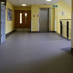 Dark stone effect flooring in a school corridor with a locker area 