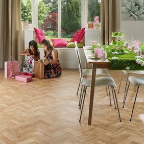 Light oak wood effect parquet flooring in a dining room with window seating area 