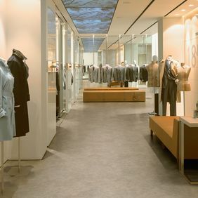High end retail shop with cloths displayed on manneqin featuring a light stone effect flooring