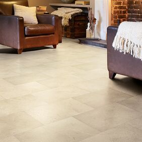 Limestone effect flooring laid in a room with an open fire and armchairs