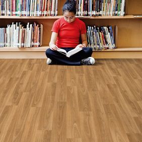 Light oak wood effect flooring in a library with a girl sat on the floor reading a book