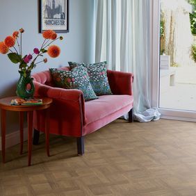 Basket weave style wood effect flooring laid in a front room with a pink couch
