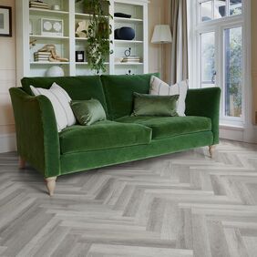 Grey coloured oak effect large parquet flooring with a green sofa