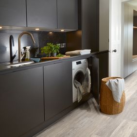 Oak effect flooring in a modern kitchen with matt black units